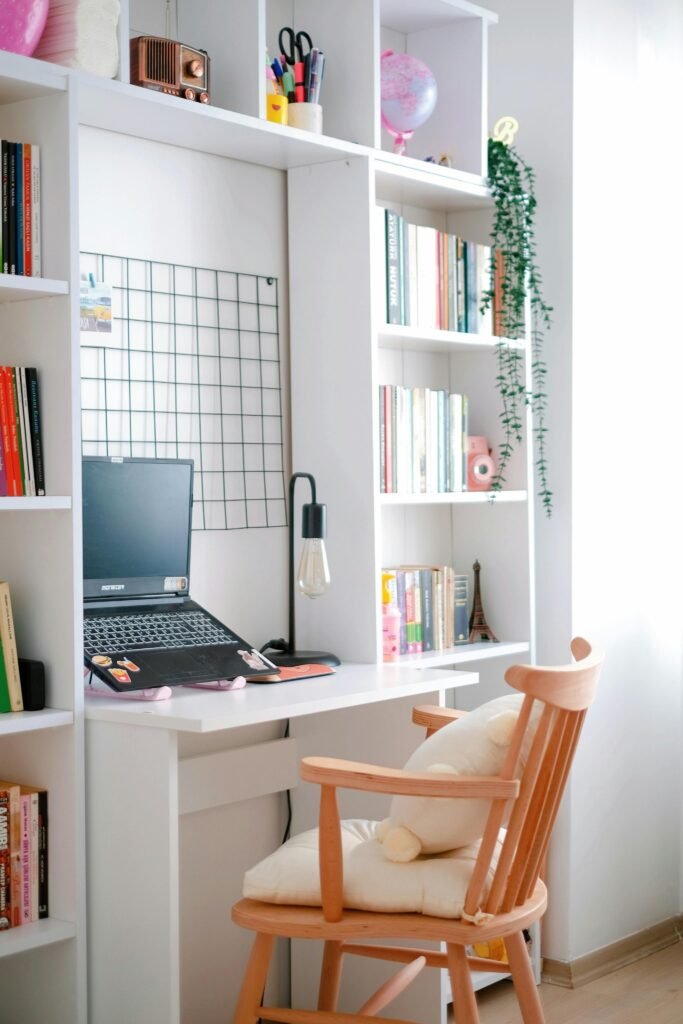 Bright and stylish home office setup with a white desk, bookshelves, and a wooden chair.